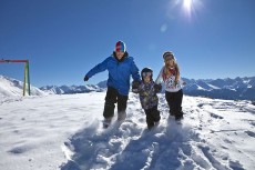 Familie im Schnee während der Kinderskiwochen in Tirol West